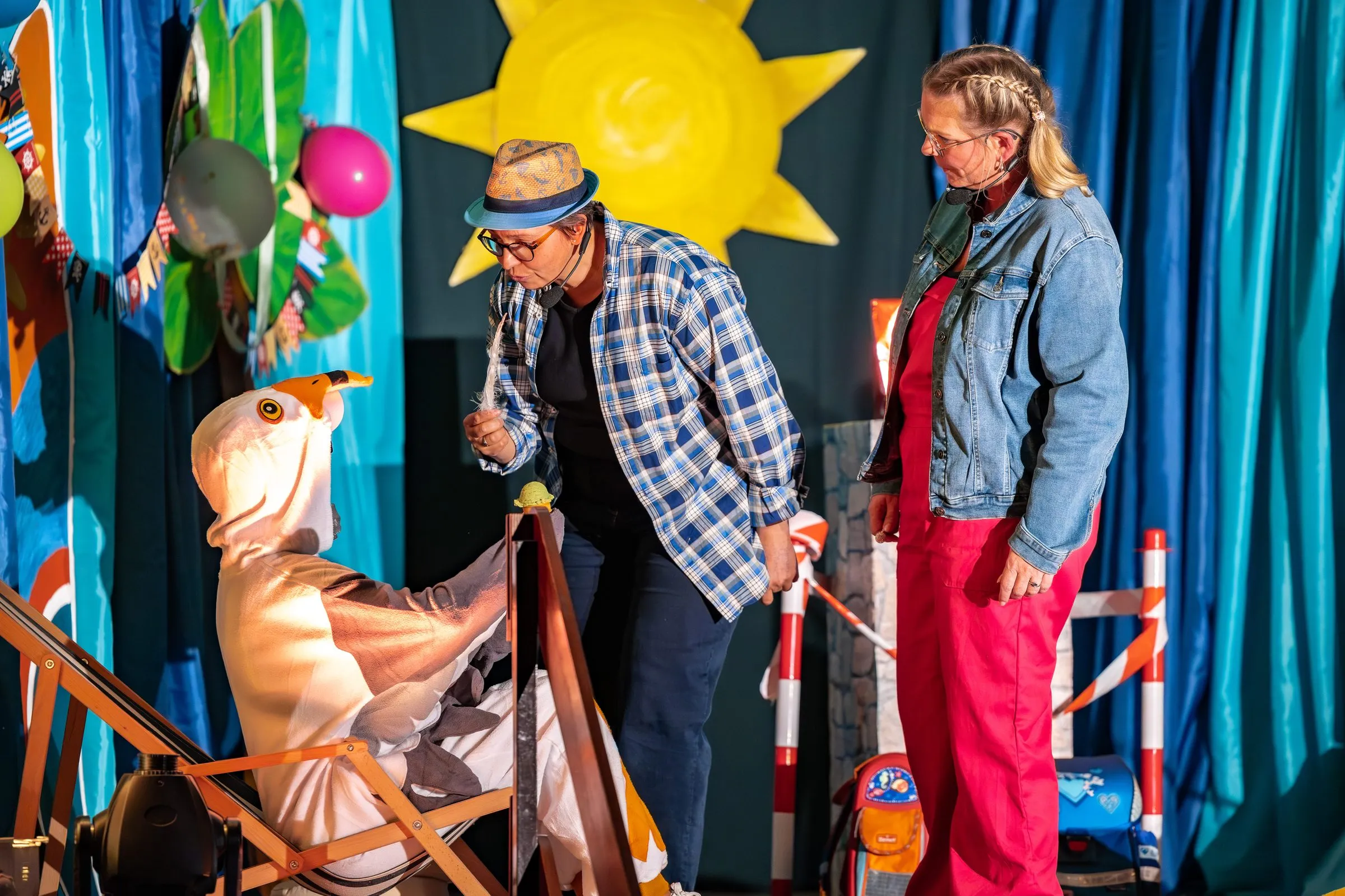 Die Möwe Lenny im Liegestuhl, zwei weitere Figuren blicken auf sie herab.