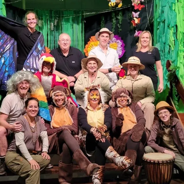 Gruppenfoto des Ensembles von „Mut tut gut – Ein Dschungel-Abenteuer“ in Kostüm — Papagei, Affen, Tiger und Forscher:innen vor der Dschungelkulisse.