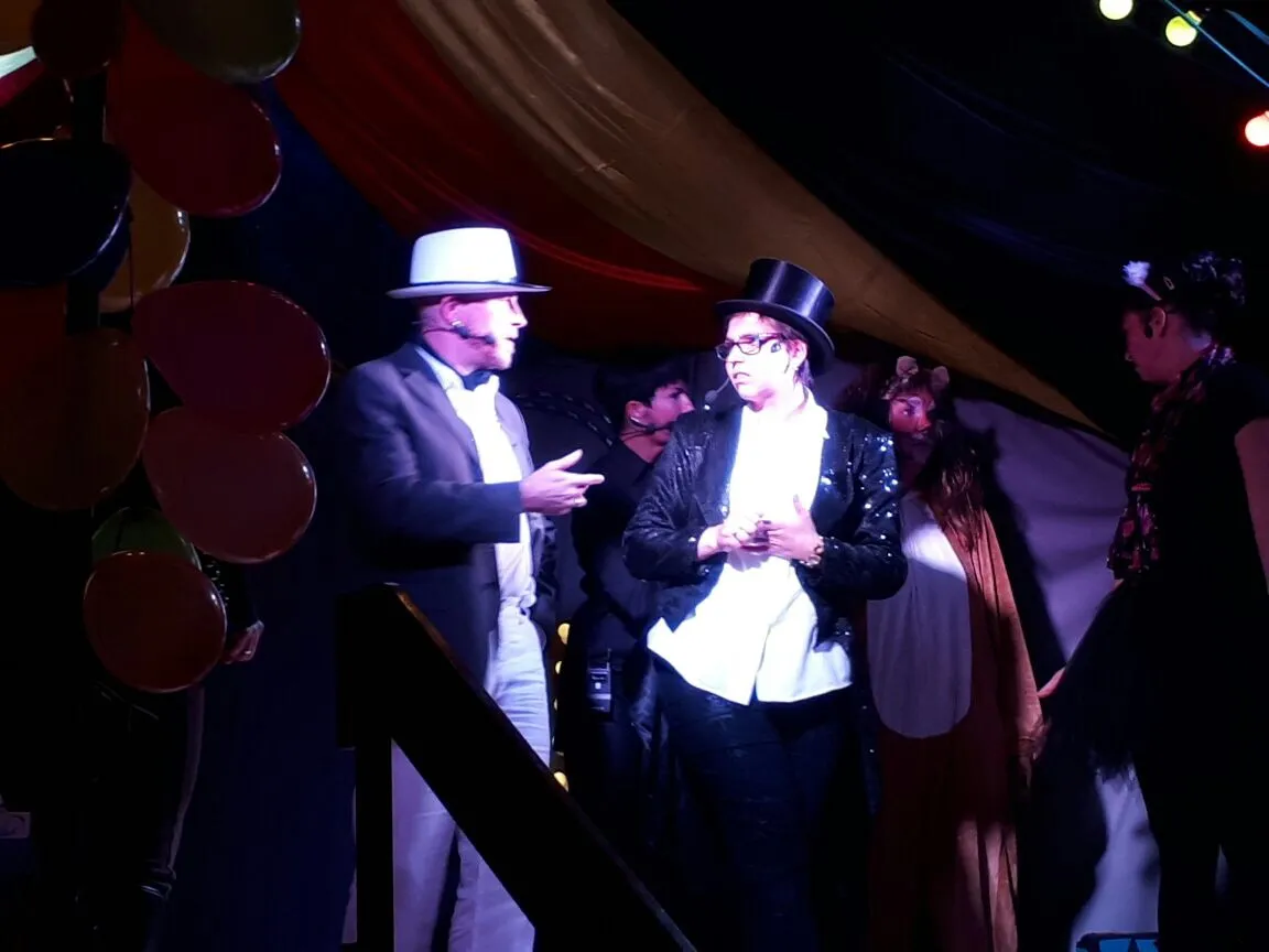 Zirkusdirektor Rudi Rossini im Gespräch mit Star-Artist Carlo Kunststück, im Hintergrund Löwe Leo.