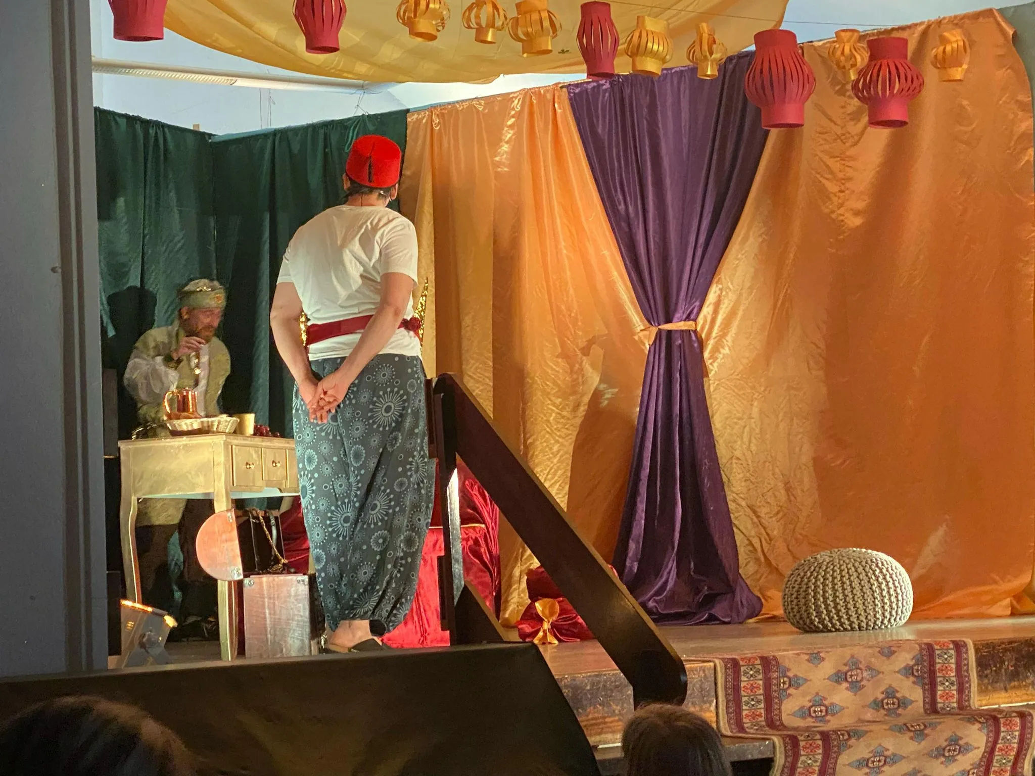 Der Sultan überreicht einer Figur in Weiß ein Schild mit der Aufschrift „Glück“, Nahaufnahme.