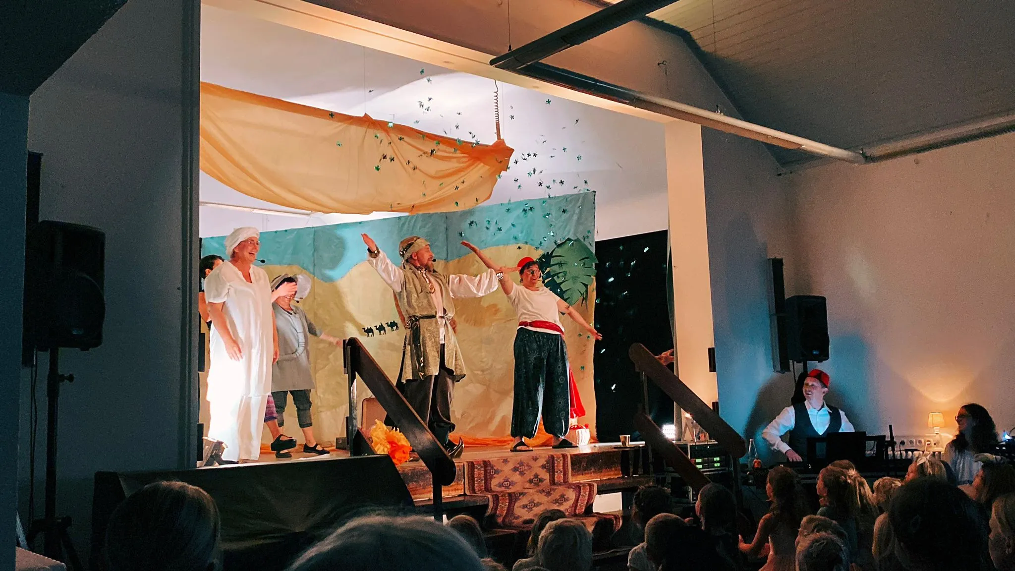 Schlussapplaus mit erhobenen Armen vor der Kulisse, Konfetti fällt von der Decke.