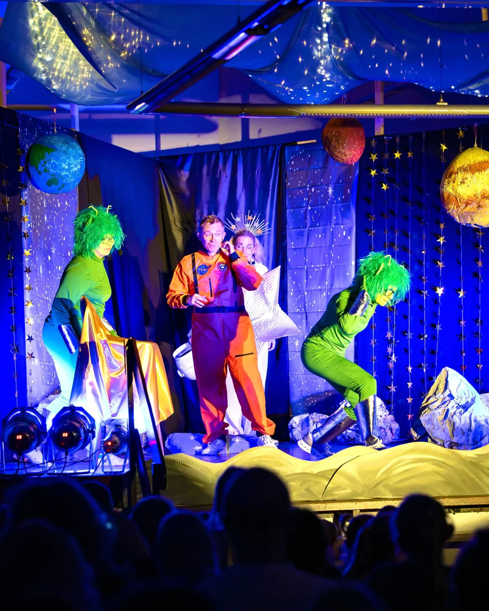 Zwei grüne Außerirdische, Edwin im Astronautenanzug und Stern Stella im Hintergrund auf der Mondkulisse.
